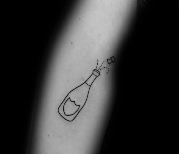 Minimalist tattoo of a champagne bottle popping on skin, with bubbles and cork depicted in simple black lines.