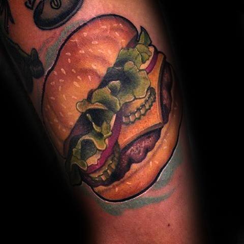 Cheeseburger tattoo with lettuce and onions graces a person's arm