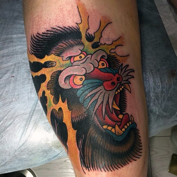 Neo-traditional baboon tattoo with bold outlines, vivid colors, and a fierce expression, featuring dynamic shading for a striking and intense leg design.