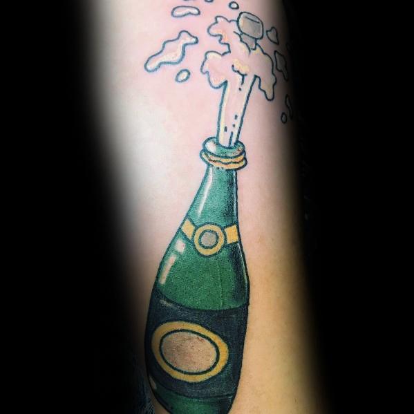 Tattoo of a green champagne bottle popping with bubbly foam on a person's skin.