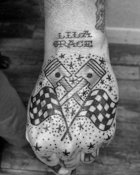 Bold hand tattoo featuring crossed pistons, checkered flags, and decorative stars, symbolizing racing passion, mechanics, and victory.