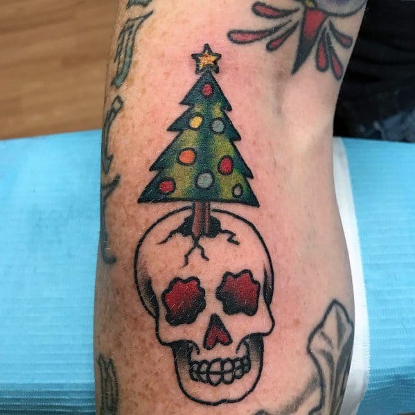 Bold Christmas tree tattoo featuring a colorful tree growing from a cracked skull, blending holiday cheer with a dark, edgy design.