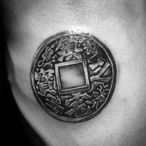 Realistic tattoo of an ancient Chinese coin with a square hole, featuring intricate characters and shading for a three-dimensional effect.