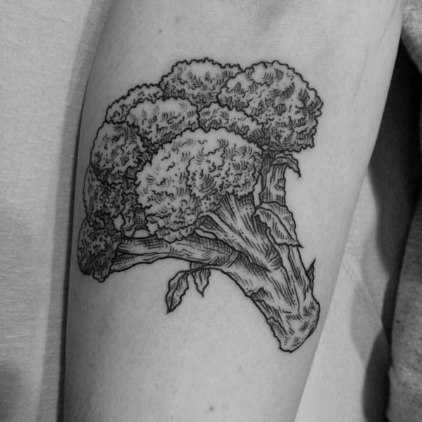 Detailed black ink broccoli tattoo on the upper arm, featuring fine linework and intricate shading for a bold yet minimalist design.