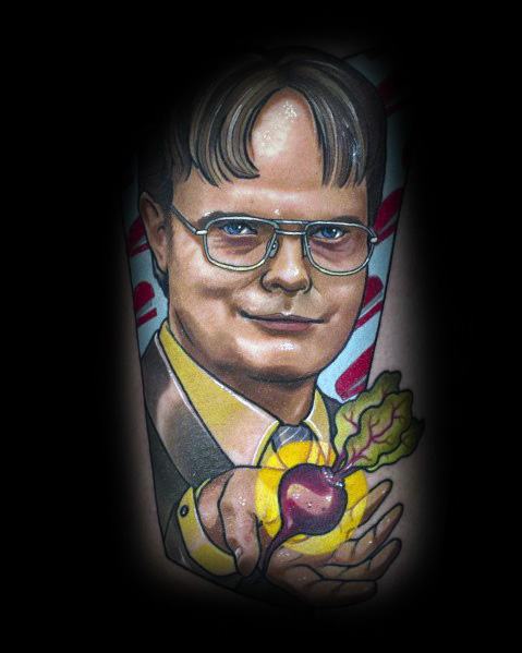 Vibrant tattoo of Dwight Schrute smiling while holding a glowing beet in his hand, featuring bold colors and detailed shading on an arm.