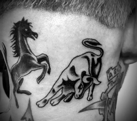 Bold tattoo of Ferrari's horse and Lamborghini's bull side-by-side, symbolizing automotive rivalry and passion, inked behind man's ear.