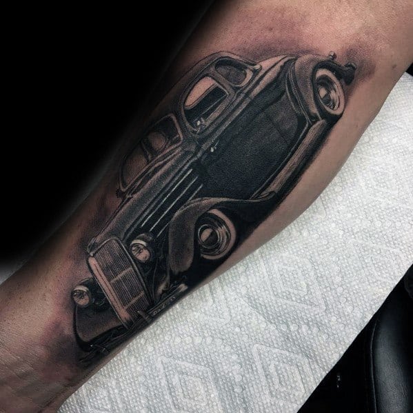Realistic black and grey vintage Ford car tattoo on forearm, featuring intricate shading, fine details, and a classic antique automobile design.