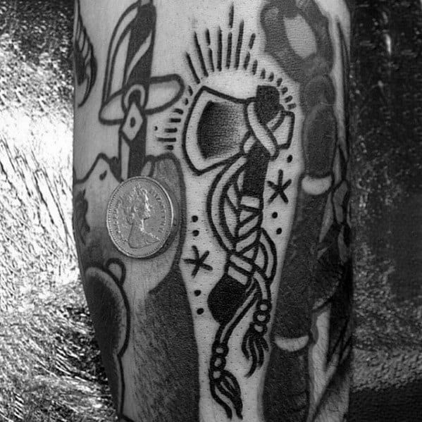 Bold blackwork hatchet tattoo with a wrapped handle and radiant details, surrounded by other traditional-style tattoos on the forearm.