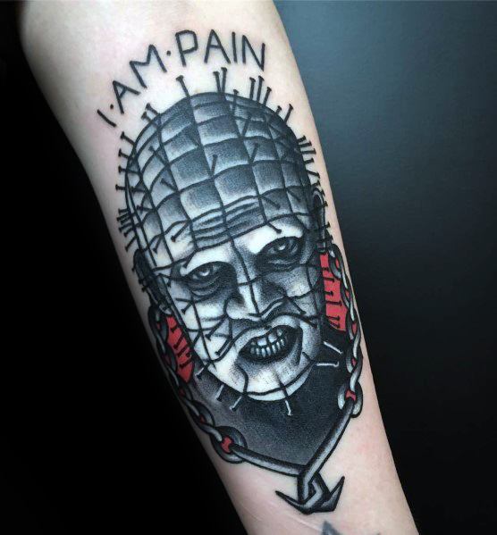 Bold *Hellraiser* tattoo of Pinhead with black and grey shading, red chain accents, and the phrase "I AM PAIN" for a striking effect.