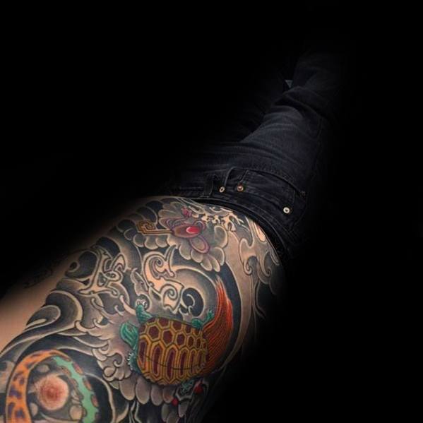 Japanese turtle tattoo on the side torso featuring bold waves, floral details, and a vibrant shell, symbolizing longevity and resilience.