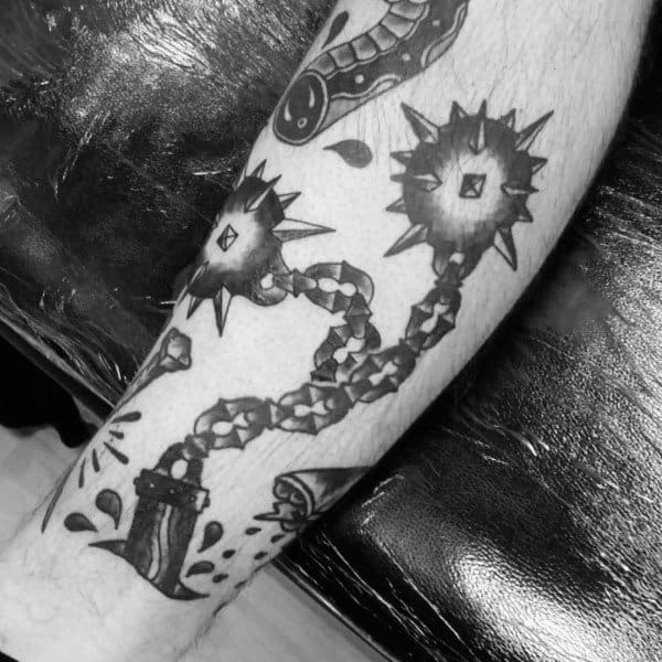 Black and gray mace tattoo featuring two spiked balls on chains, striking with force, symbolizing power, resilience, and medieval warfare.