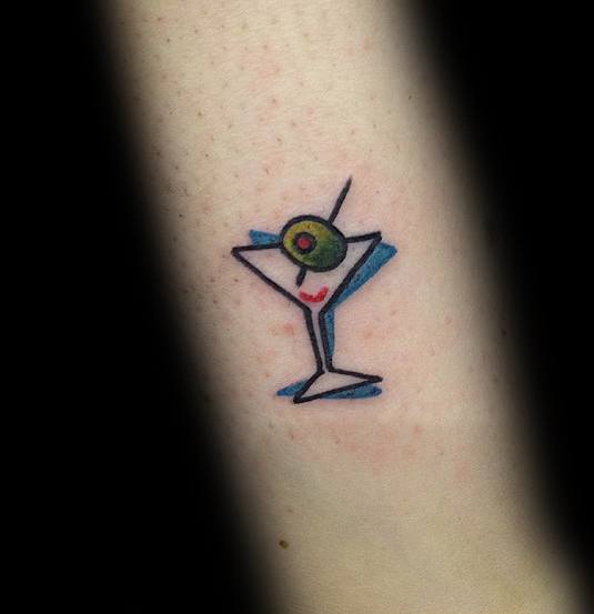 Minimalist martini glass tattoo with a geometric outline, featuring an olive garnish. A simple yet stylish design with bold black and blue lines.