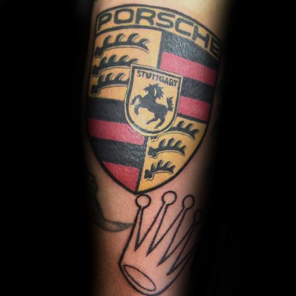 Colorful Porsche crest tattoo with black, red, and gold detailing on a man's forearm.