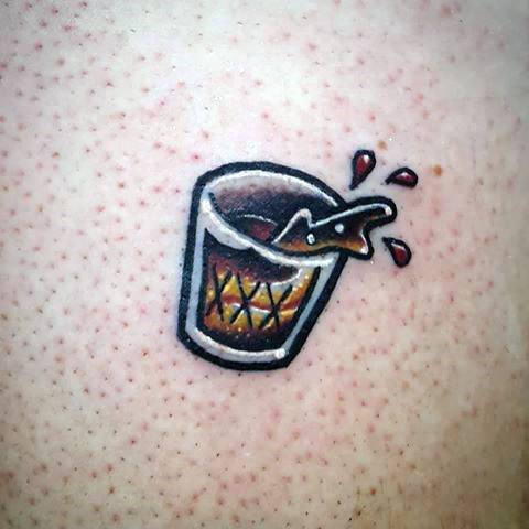 Small shot glass tattoo with a bold outline, featuring a whiskey drink splashing out, designed in a cartoonish style for a fun look.