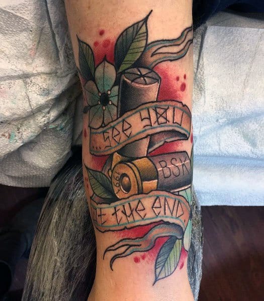 Shotgun shell tattoo with banners reading "See Hell See the End," surrounded by flowers and leaves, featuring bold colors and shading.