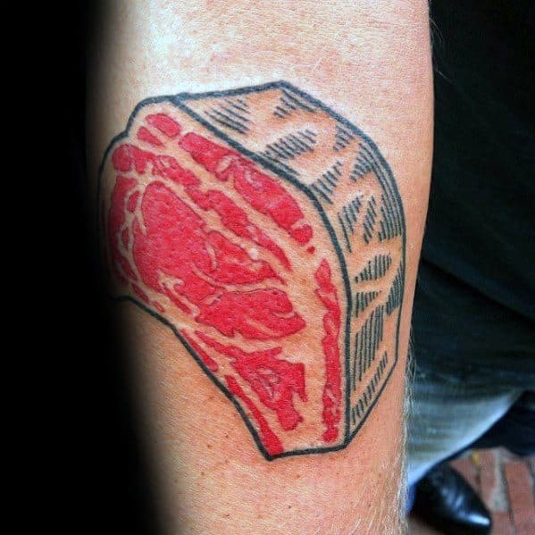 Tattoo of a thick-cut steak with bold red and black shading, featuring a textured fat cap for a striking and graphic meat-inspired design