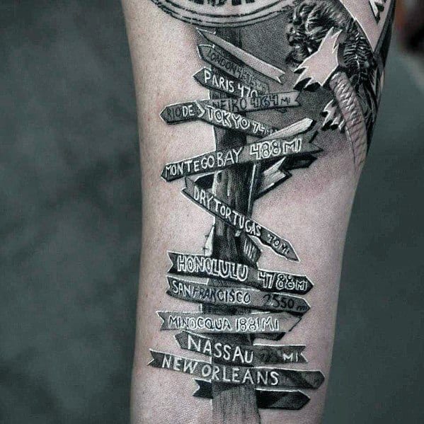 Black and grey tattoo of a detailed signpost with multiple destination signs, including Paris, Tokyo, Honolulu, and New Orleans.