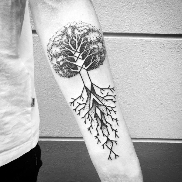 Forearm tattoo of a tree with intricate branches and roots in black ink against the skin