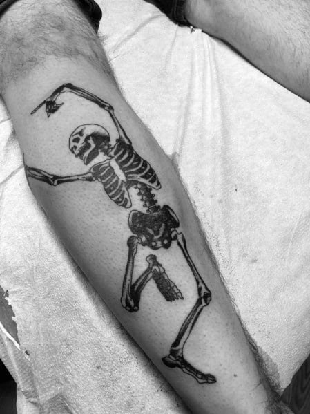 Dancing skeleton tattoo with raised arms and a playful pose, inked in bold black for a striking and energetic design on the leg.