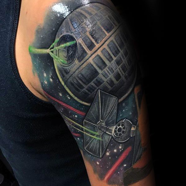 Tattoo of a Death Star and spacecraft on an arm, with stars and colorful effects