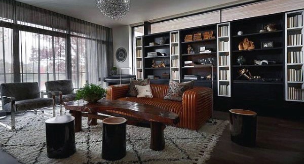 Sleek living area with leather sofa, wood coffee table, modern bookshelves, and large windows.