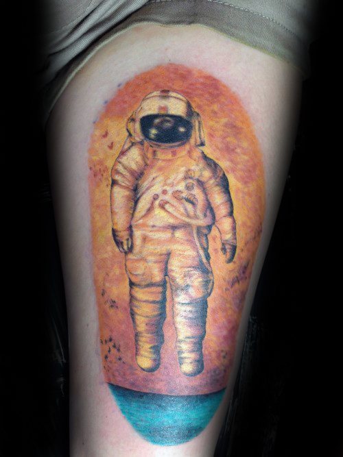 Deja Entendu astronaut tattoo featuring warm orange tones, black birds, and a calm teal ocean at the bottom for contrast.