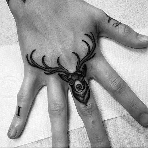 Small black and grey elk tattoo on the hand, with detailed antlers extending across the fingers for a unique and bold design.
