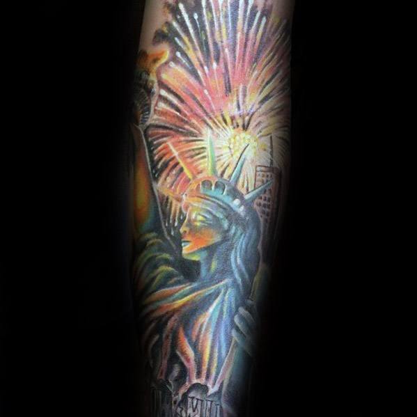 Tattoo of the Statue of Liberty with vibrant fireworks bursting behind, creating a patriotic and dynamic design with detailed shading and bold colors.