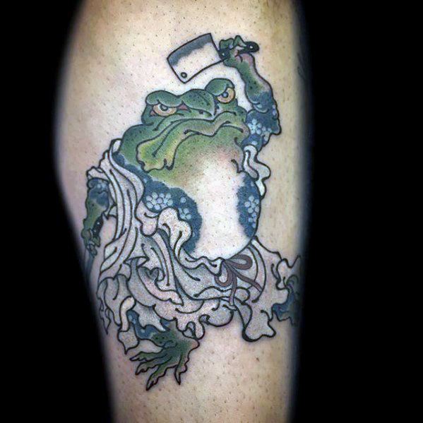 Japanese-style tattoo of a fierce green frog holding a cleaver, dressed in flowing robes with intricate patterns, symbolizing strength and warrior spirit.