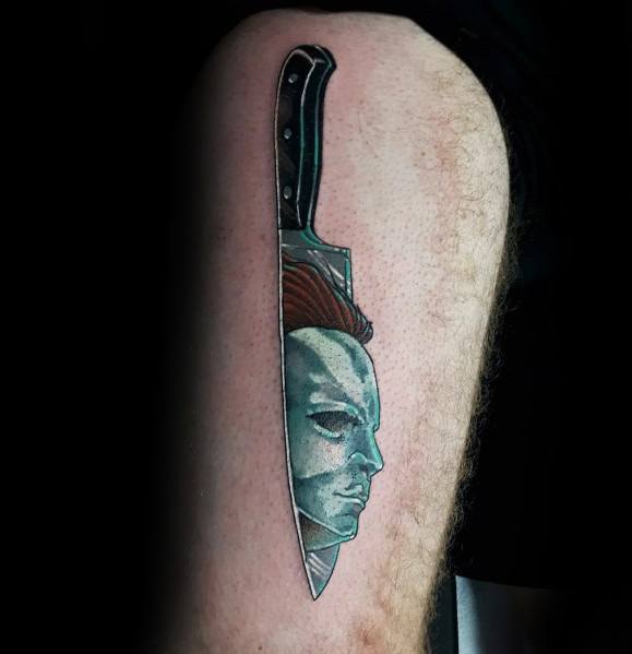 Michael Myers-themed tattoo of a knife reflecting his iconic mask, blending horror aesthetics with sharp, detailed realism.