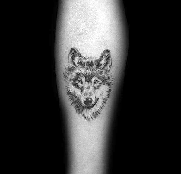 Small realistic Siberian Husky tattoo on a man's forearm, featuring fine shading and intricate fur details for a subtle yet lifelike design.