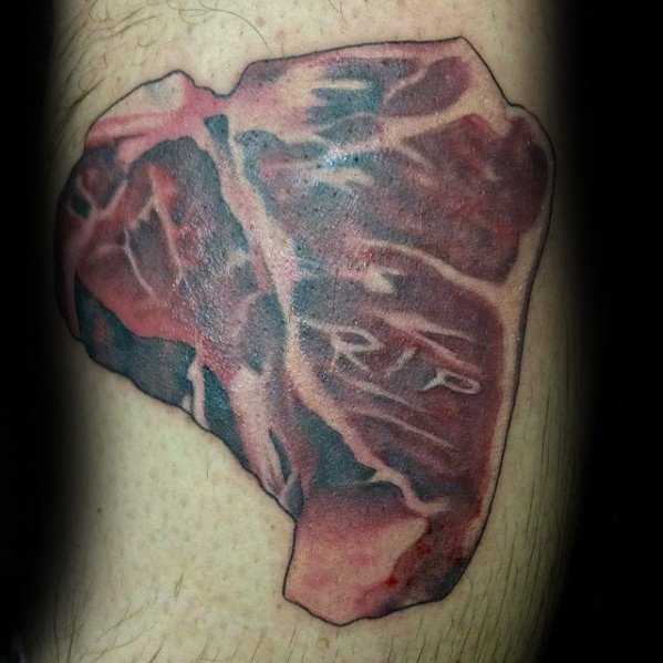 Tattoo of a realistic raw steak with marbling details, featuring the letters RIP subtly carved into the meat for a bold and dark design