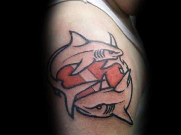 Tattoo of two sharks circling a red and white dive flag, symbolizing balance, strength, and a deep connection to the ocean and diving.