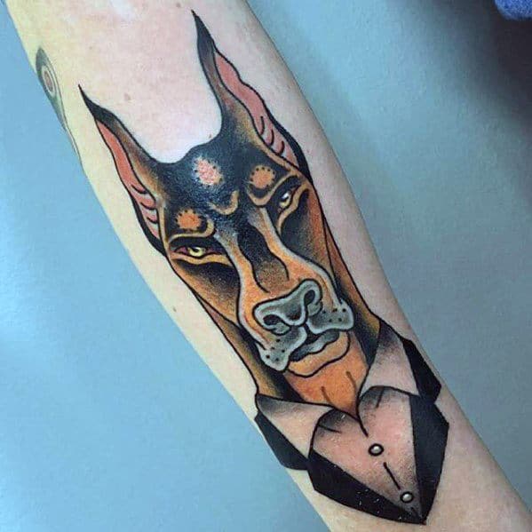 Stylized Doberman tattoo with sharp features, wearing a suit, blending anthropomorphic design with bold traditional color tones.