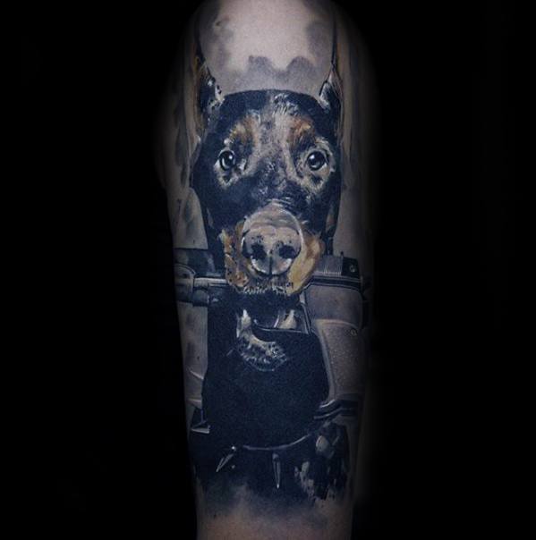 Hyper-realistic Doberman tattoo in tactical gear, with intense eyes and dark tones, creating a powerful military or K9-inspired design.