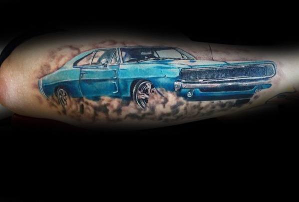 Realistic blue Dodge Charger tattoo with a smoky burnout effect, showcasing a bold and dynamic muscle car design on the arm.
