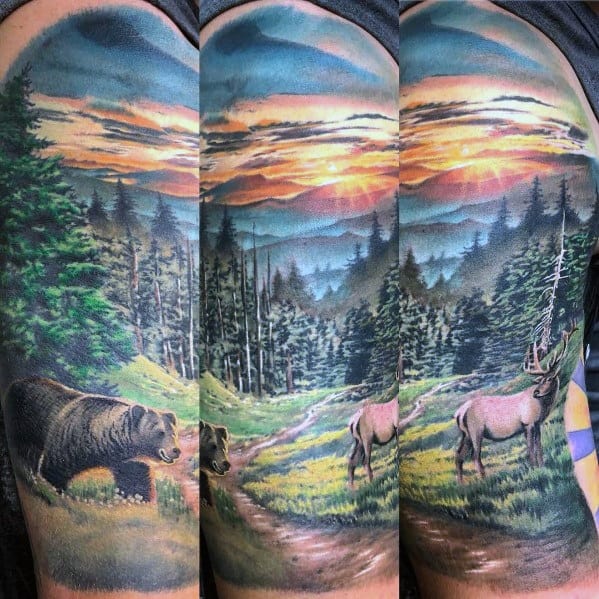 Vibrant full-sleeve wildlife tattoo featuring elk, a bear, and a scenic mountain landscape with a sunset for a bold and immersive nature design.