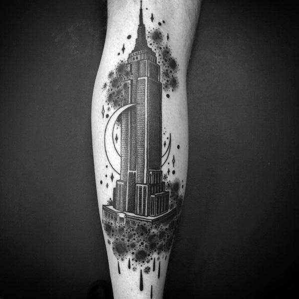 Empire State Building tattoo with celestial elements, featuring stars, a crescent moon, and abstract shading in bold black ink.