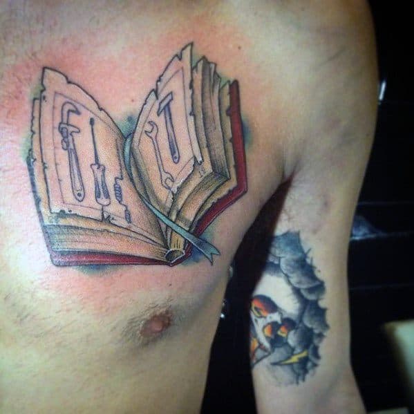 Tattoo of an open book on the chest with illustrated tools like screwdrivers inside its pages, blending craftsmanship with storytelling in bold color.