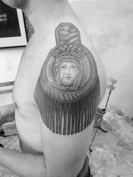 Epaulette tattoo featuring a crowned portrait of a saint-like figure, framed by intricate braids and long, uniform tassels.