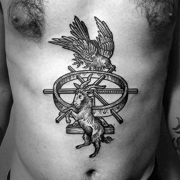 Tattoo of a raven above a horned goat standing before a spoked wheel, blending mythological and symbolic imagery on the torso.