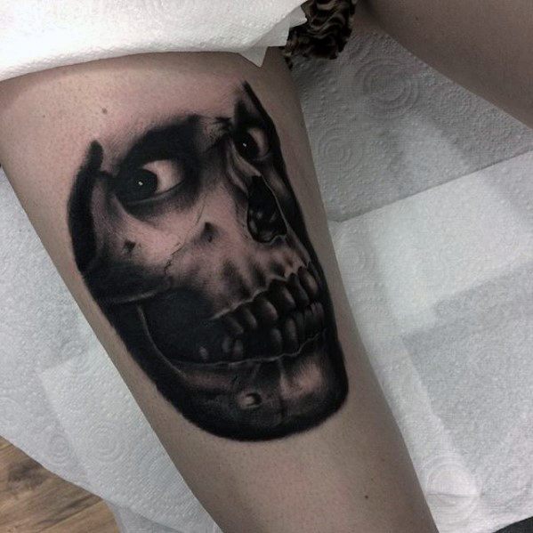 Black and grey Evil Dead tattoo of a half-decayed skull with a single intense eye peering out, creating a chilling undead stare