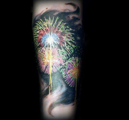 Tattoo of vibrant fireworks in green, pink, and yellow against a dark smoky background, creating a striking and dynamic night-sky effect.