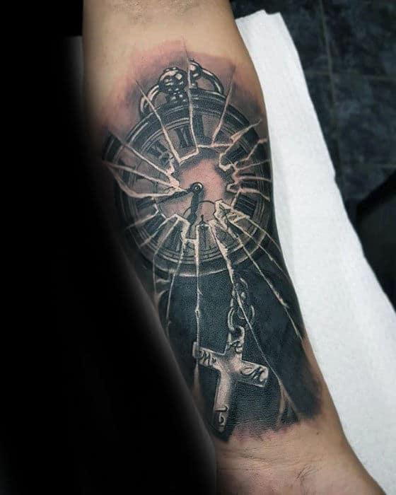 Tattoo of a broken clock with a cross hanging from one of the clock hands on an arm