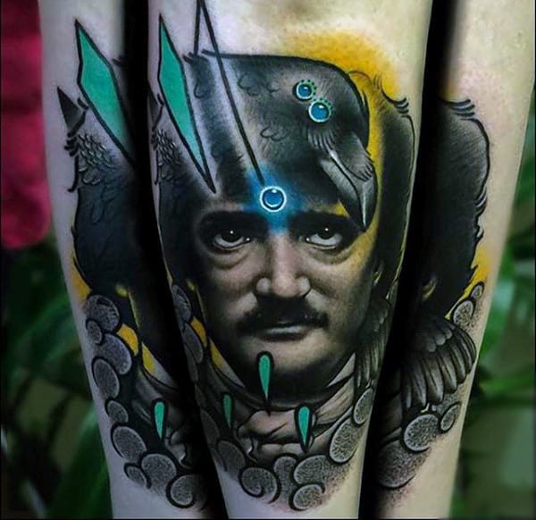 Tattoo of a man's face with raven, feathers, and a swirling green pattern on an arm