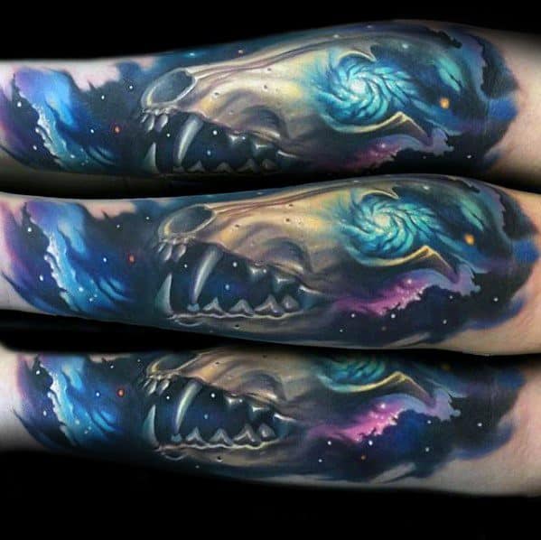 Vivid tattoo of a fox skull blended with a galaxy theme, featuring swirling nebulas, stars, and cosmic colors across the forearm.