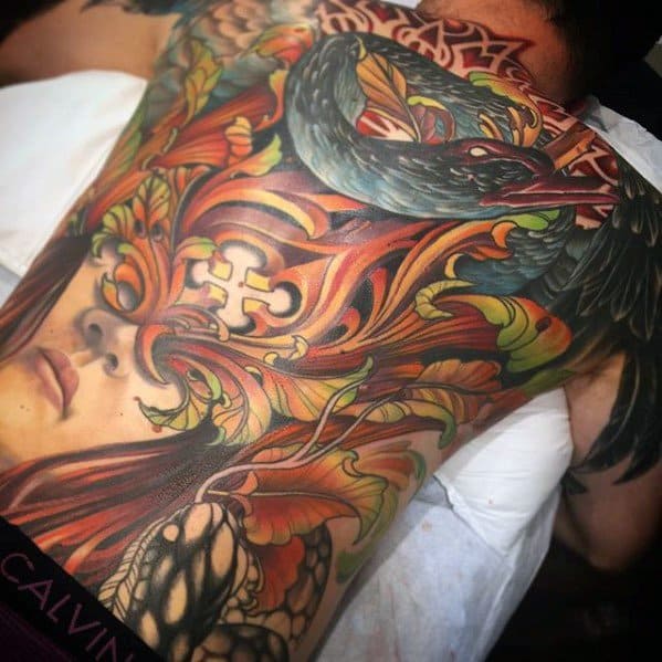 Vibrant full-back tattoo featuring a black swan, a woman’s face, and swirling ornamental flames in bold red, orange, and green tones.