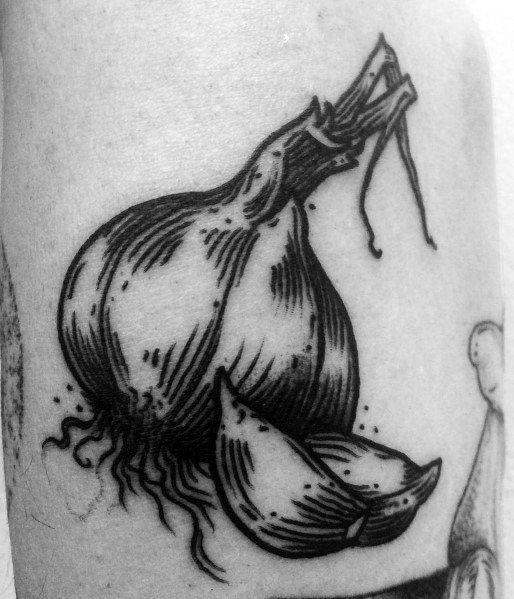 Bold black ink garlic tattoo with fine line shading and peeled cloves, creating a detailed and textured botanical design.