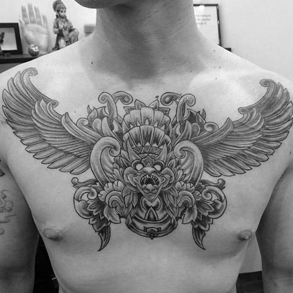 Garuda tattoo design across the chest with detailed wings, ornate patterns, and a powerful deity face at the center.