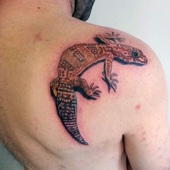 Colorful gecko tattoo on upper back with orange and brown tones, detailed scales, and a lifelike crawling pose.